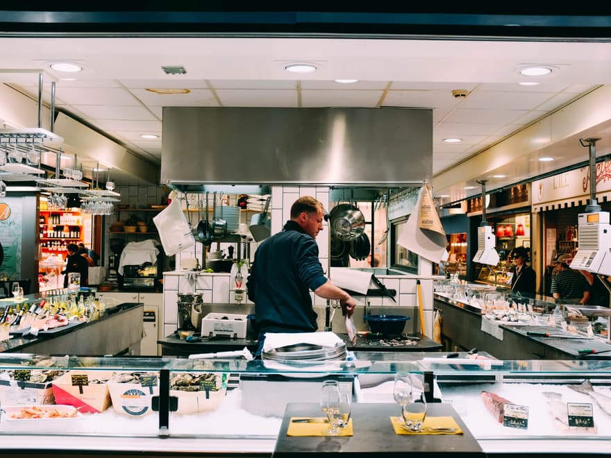 Shopkeeper serving behind a busy food counter