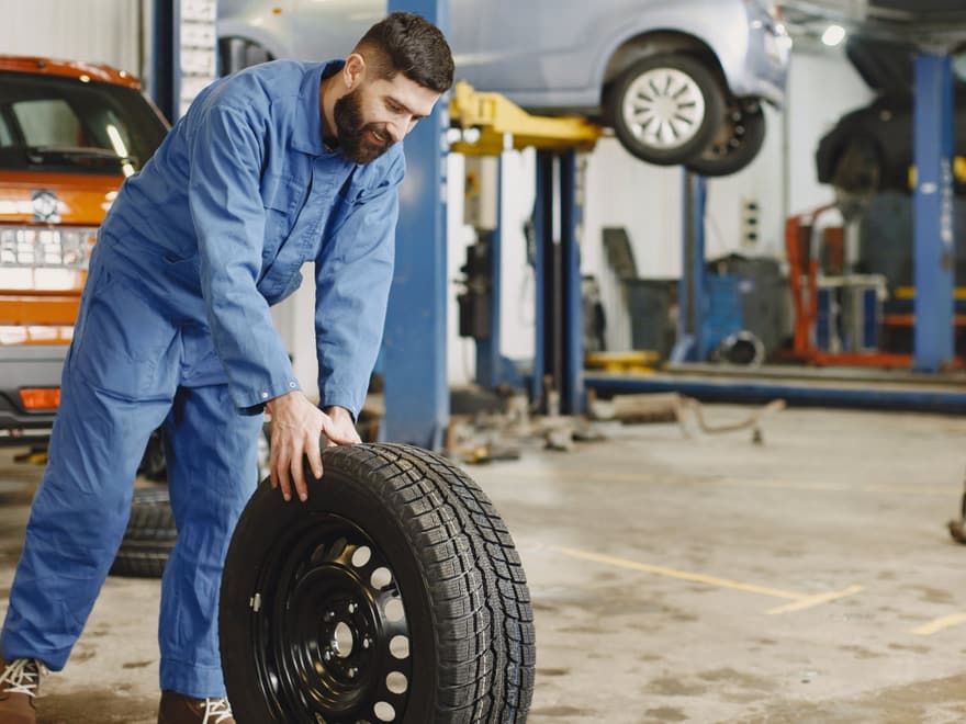 Tyre fitter rolling a new tyre across the workshop